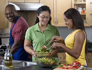 Une famille dans la cuisine préparant une salade.